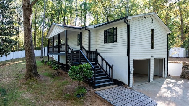 ranch-style house with concrete driveway, stairway, an attached garage, fence, and a porch