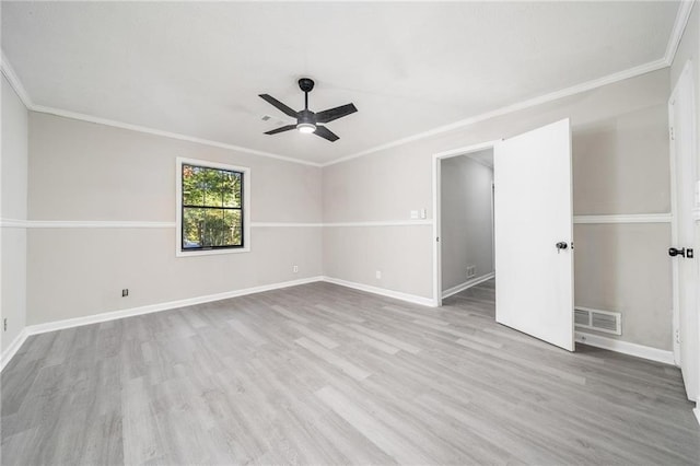 spare room featuring baseboards, light wood finished floors, visible vents, and crown molding