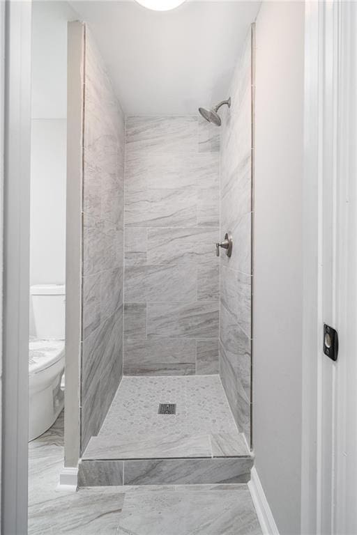 bathroom with tiled shower and toilet