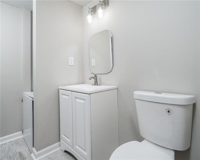 bathroom featuring toilet, baseboards, and vanity