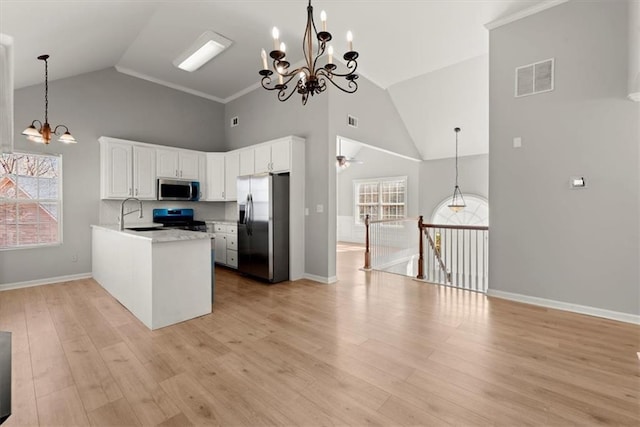 kitchen featuring hanging light fixtures, light hardwood / wood-style flooring, appliances with stainless steel finishes, ceiling fan with notable chandelier, and white cabinets