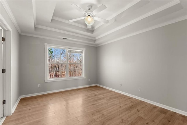 spare room featuring ceiling fan, ornamental molding, light wood-type flooring, and a tray ceiling