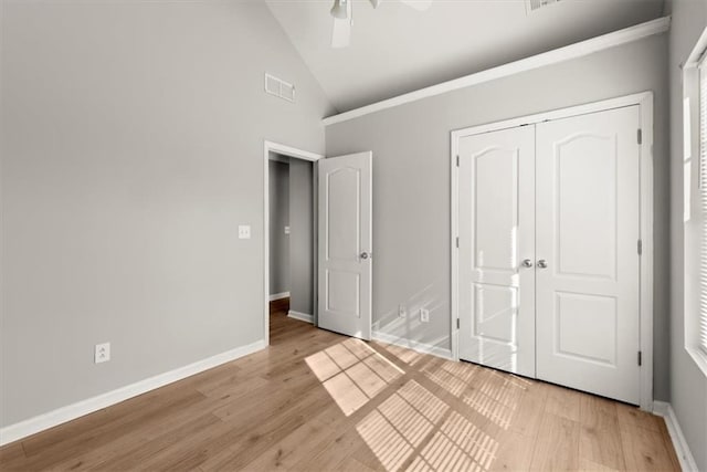 unfurnished bedroom featuring light hardwood / wood-style flooring, high vaulted ceiling, a closet, and ceiling fan