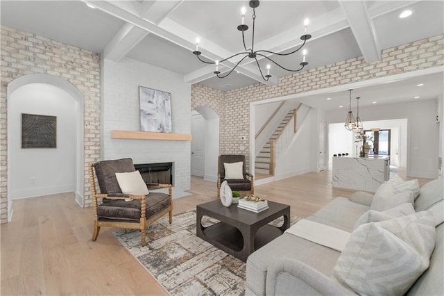 living room with brick wall, a fireplace, and light hardwood / wood-style flooring