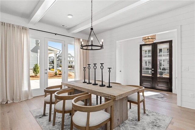 dining space featuring beam ceiling, an inviting chandelier, and light hardwood / wood-style floors