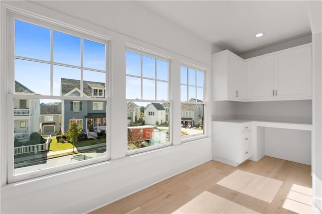 interior space featuring plenty of natural light, built in desk, and light hardwood / wood-style flooring