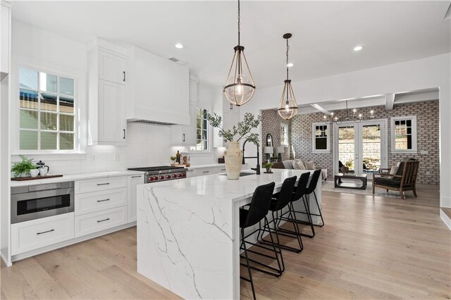 kitchen featuring plenty of natural light, a center island with sink, and white cabinets