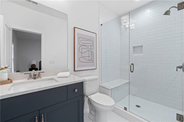 bathroom with vanity, walk in shower, tile patterned floors, and toilet