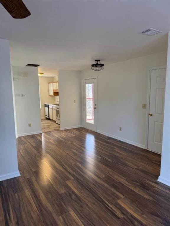 unfurnished living room with a ceiling fan, dark wood finished floors, visible vents, and baseboards