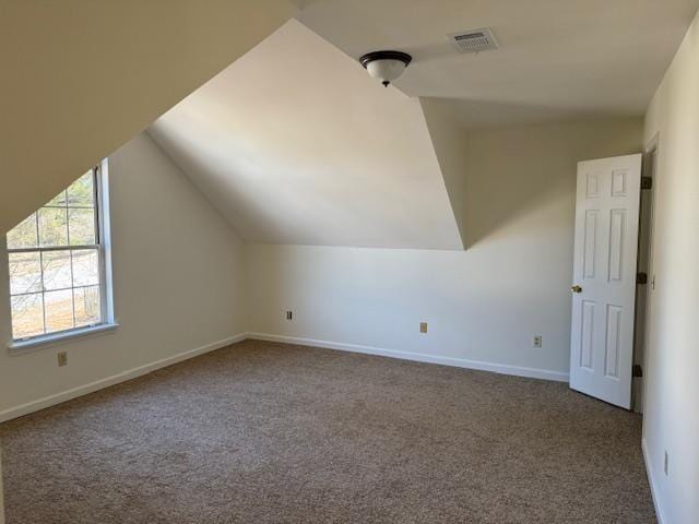 additional living space with carpet floors, visible vents, baseboards, and vaulted ceiling