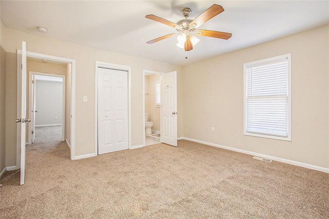 unfurnished bedroom featuring ceiling fan, light colored carpet, and connected bathroom