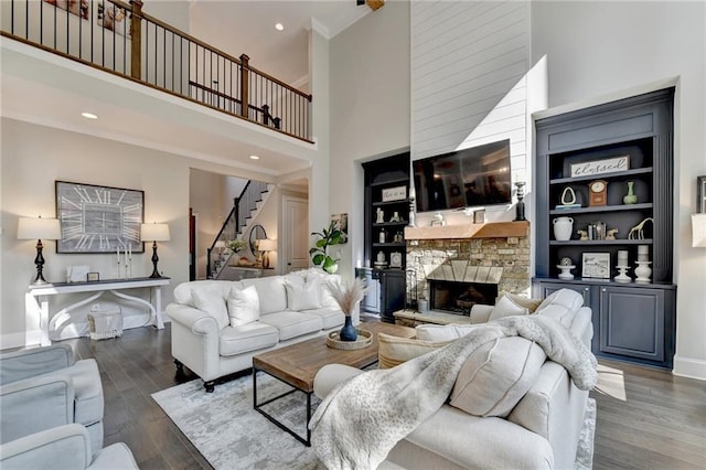 living room with dark wood-type flooring, crown molding, a high ceiling, and a fireplace