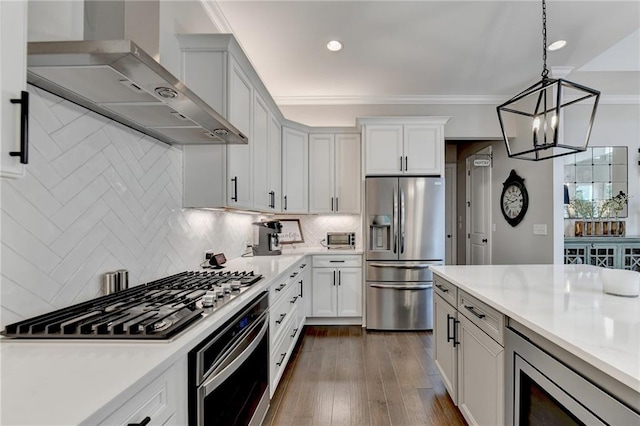 kitchen featuring hanging light fixtures, ornamental molding, dark hardwood / wood-style floors, wall chimney exhaust hood, and stainless steel appliances