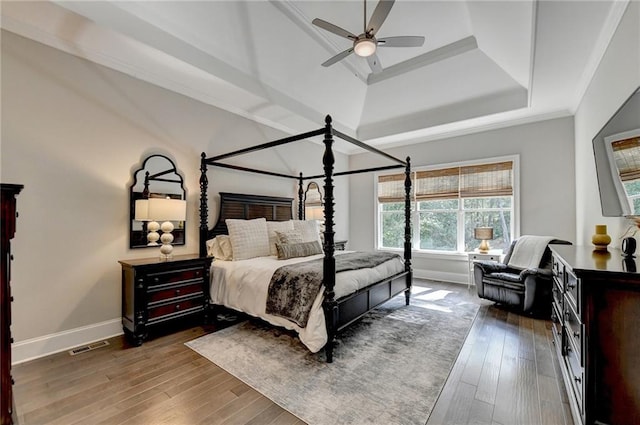 bedroom featuring crown molding, dark wood-type flooring, a raised ceiling, and ceiling fan