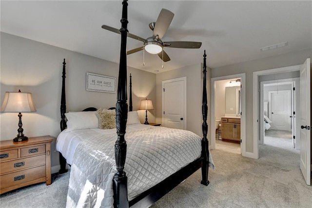 bedroom with light carpet, ensuite bathroom, and ceiling fan