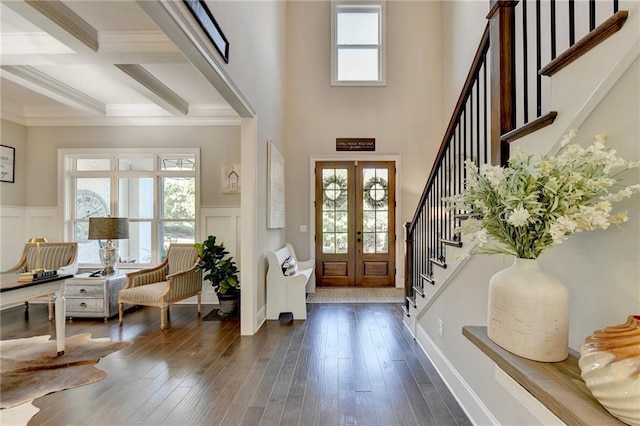 foyer entrance featuring french doors, coffered ceiling, beam ceiling, dark wood-type flooring, and crown molding