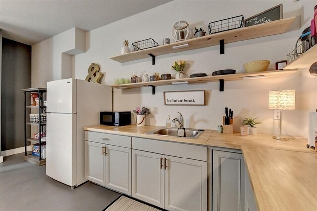 kitchen with white fridge, sink, gray cabinetry, and wooden counters