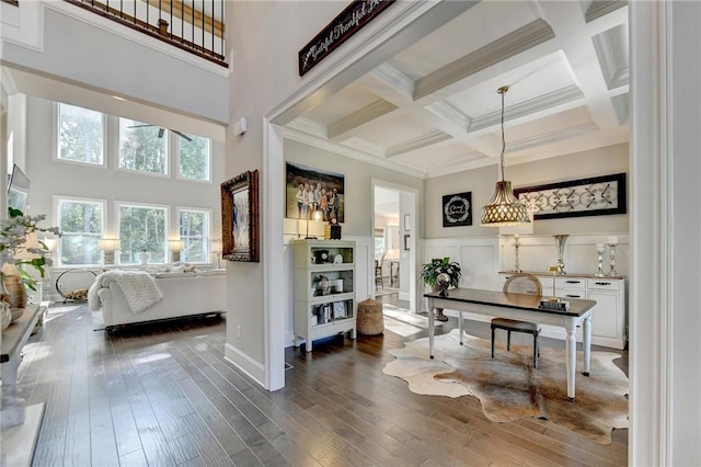 interior space with white cabinets, beam ceiling, dark hardwood / wood-style floors, pendant lighting, and coffered ceiling