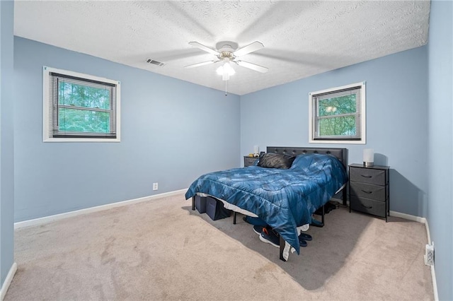 carpeted bedroom with ceiling fan and a textured ceiling