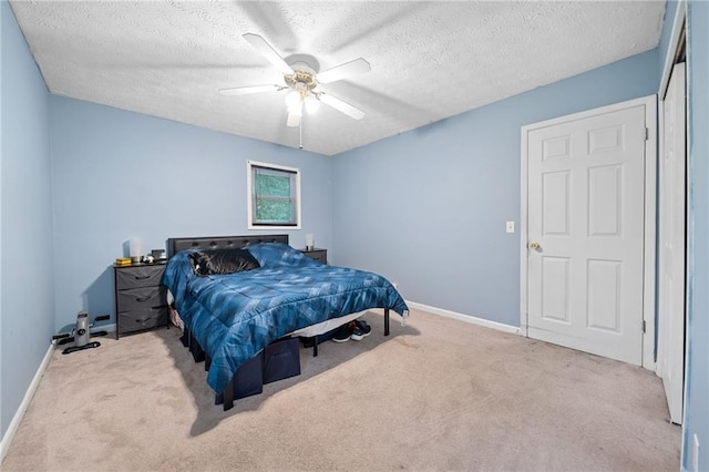 bedroom with a textured ceiling, light colored carpet, and ceiling fan