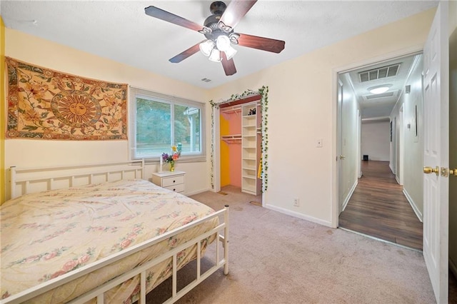 bedroom featuring carpet, ceiling fan, a walk in closet, and a closet