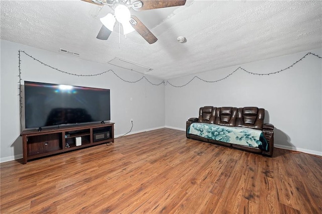 living area with ceiling fan, a textured ceiling, and hardwood / wood-style flooring