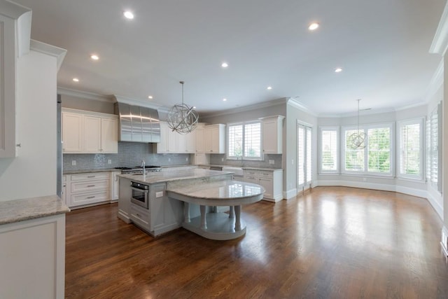 22 Mount Paran Rd, Atlanta, GA 30327 - kitchen with crown molding, an island with sink, wall chimney range hood, decorative backsplash, and dark wood-style flooring