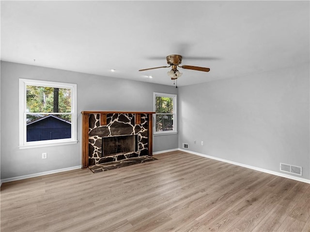 unfurnished living room with ceiling fan, a fireplace, and light hardwood / wood-style floors