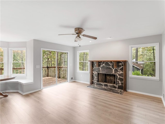 unfurnished living room featuring ceiling fan, light wood-type flooring, a healthy amount of sunlight, and a fireplace