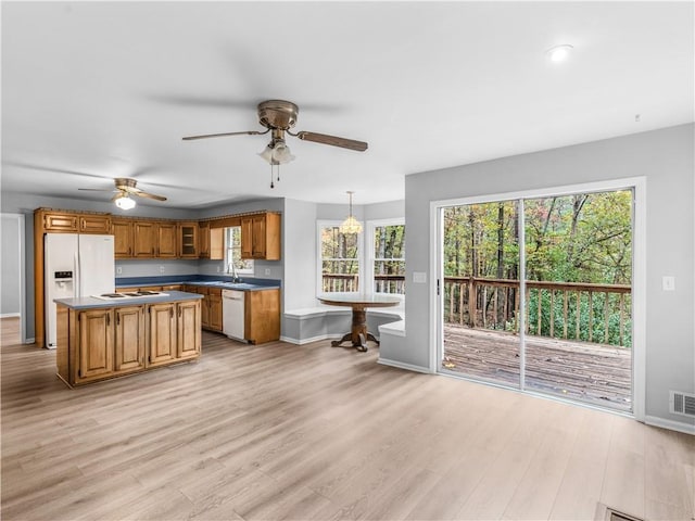 kitchen featuring plenty of natural light, white appliances, a kitchen island, pendant lighting, and ceiling fan with notable chandelier