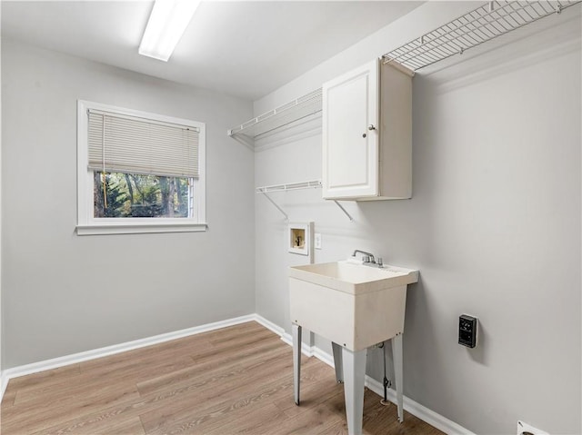 laundry room featuring light hardwood / wood-style flooring, hookup for a washing machine, and cabinets