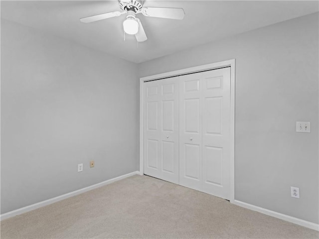 unfurnished bedroom featuring ceiling fan, a closet, and light colored carpet