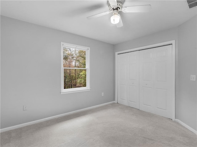 unfurnished bedroom featuring ceiling fan, light colored carpet, and a closet