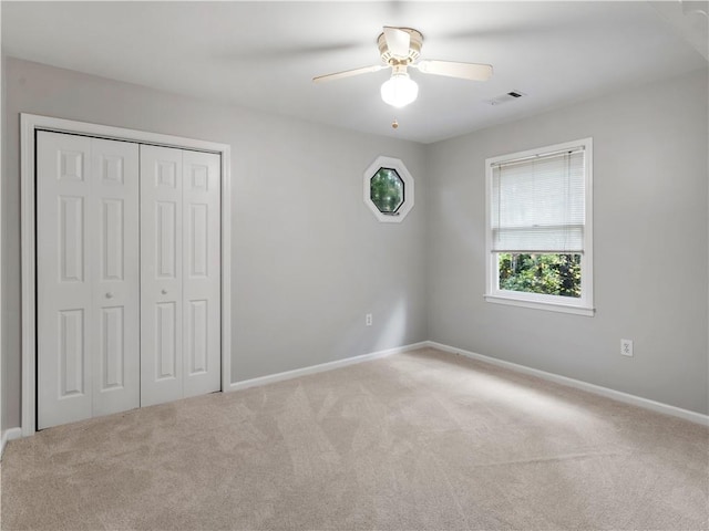 unfurnished bedroom with ceiling fan, light colored carpet, and a closet