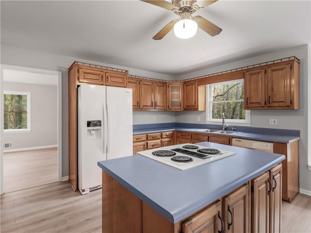 kitchen with white appliances, a kitchen island, sink, light wood-type flooring, and ceiling fan