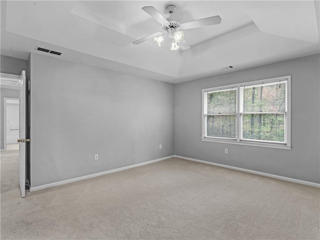 carpeted spare room with ceiling fan and a raised ceiling