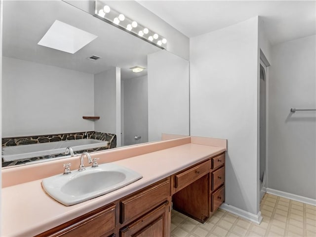 bathroom featuring a tub, vanity, and a skylight