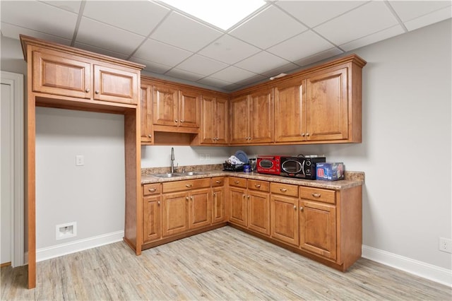 kitchen with sink, a paneled ceiling, and light hardwood / wood-style floors