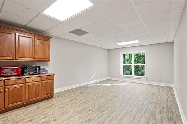 interior space with a paneled ceiling and light hardwood / wood-style flooring