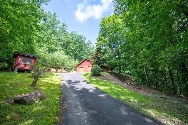 709 Deerfield Ln NW, Sugar Valley, GA 30746 - view of front of property with an outdoor structure, a detached garage, log siding, a wooded view, and a front yard