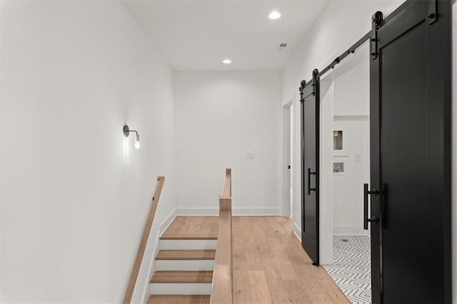 corridor with a barn door and light hardwood / wood-style flooring