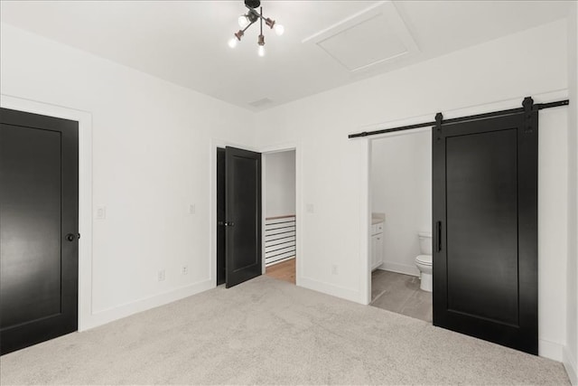 unfurnished bedroom with a barn door, light colored carpet, and connected bathroom