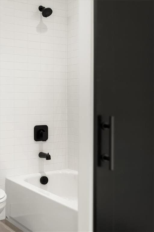 bathroom with toilet and tiled shower / bath