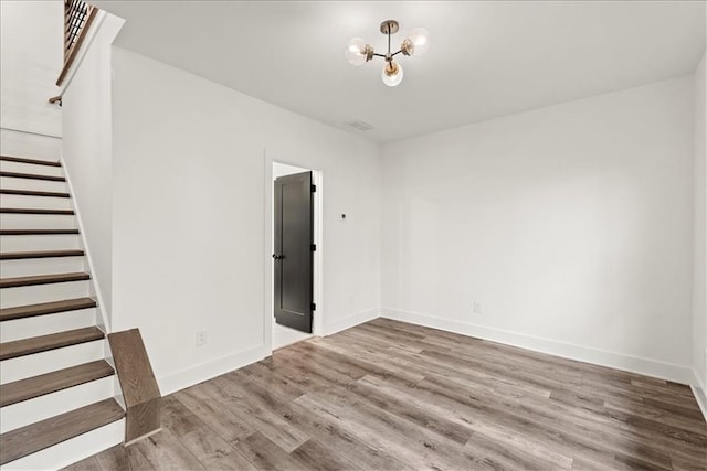 unfurnished room with an inviting chandelier and hardwood / wood-style flooring