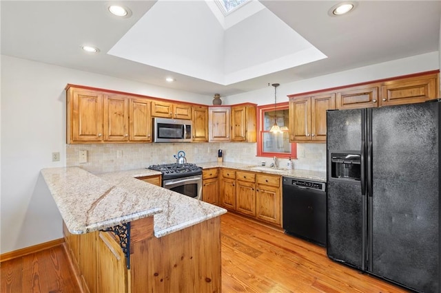 kitchen with black appliances, hanging light fixtures, brown cabinetry, and a peninsula