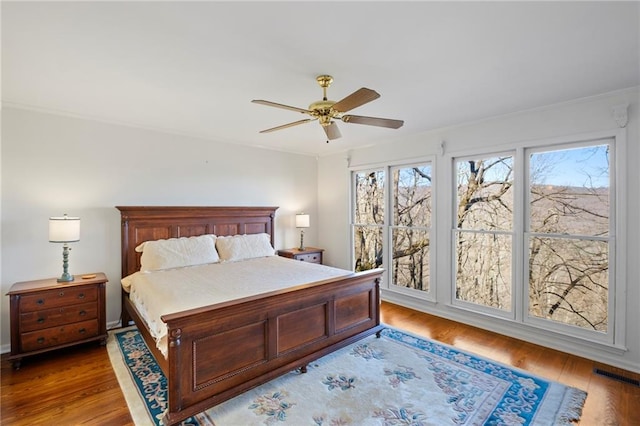 bedroom featuring ceiling fan, visible vents, and wood finished floors