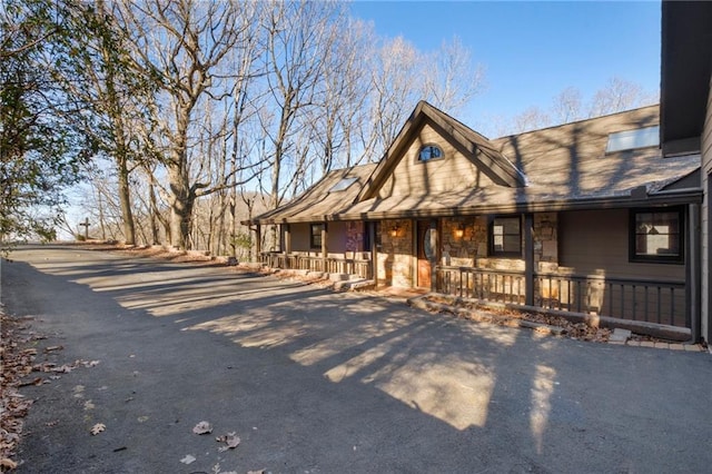 view of front of property featuring stone siding, a porch, and aphalt driveway