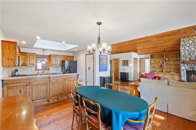 dining area featuring light wood-type flooring, a skylight, a tray ceiling, and recessed lighting