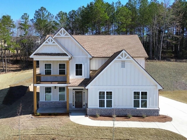 view of front of property featuring brick siding, board and batten siding, and a shingled roof