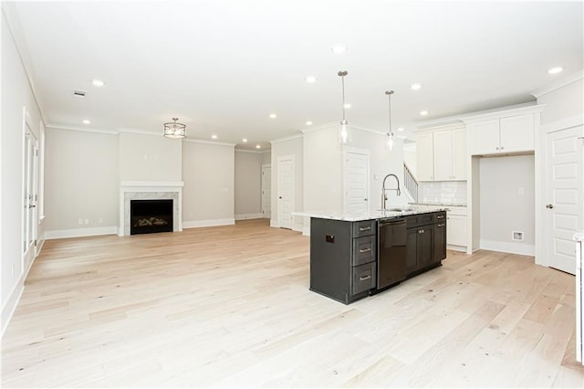 kitchen with dishwashing machine, a fireplace, a kitchen island with sink, white cabinets, and backsplash